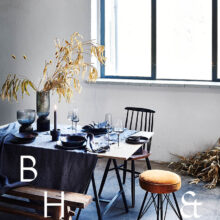 Interior photography of black table setting with dark linen and black tableware decorated with dry bamboo in scandinavian industrial loft