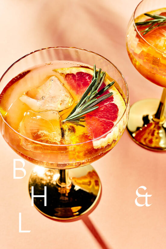 Closeup of summer cocktails and drinks with blood orange and rosemary on coral background