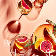 Flatlay of glasses and summer cocktails with bloodorange and grapefruit on coral background