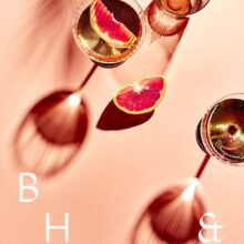 Flatlay of glasses and summer cocktails with bloodorange and grapefruit on coral background