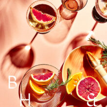 Flatlay of glasses and summer cocktails with bloodorange and grapefruit on coral background