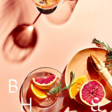 Flatlay of glasses and summer cocktails with bloodorange and grapefruit on coral background