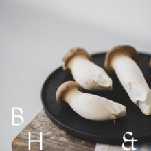 Food photography of french horn mushroom on a black plate with natural tones towels on a bench as a close up in perspective