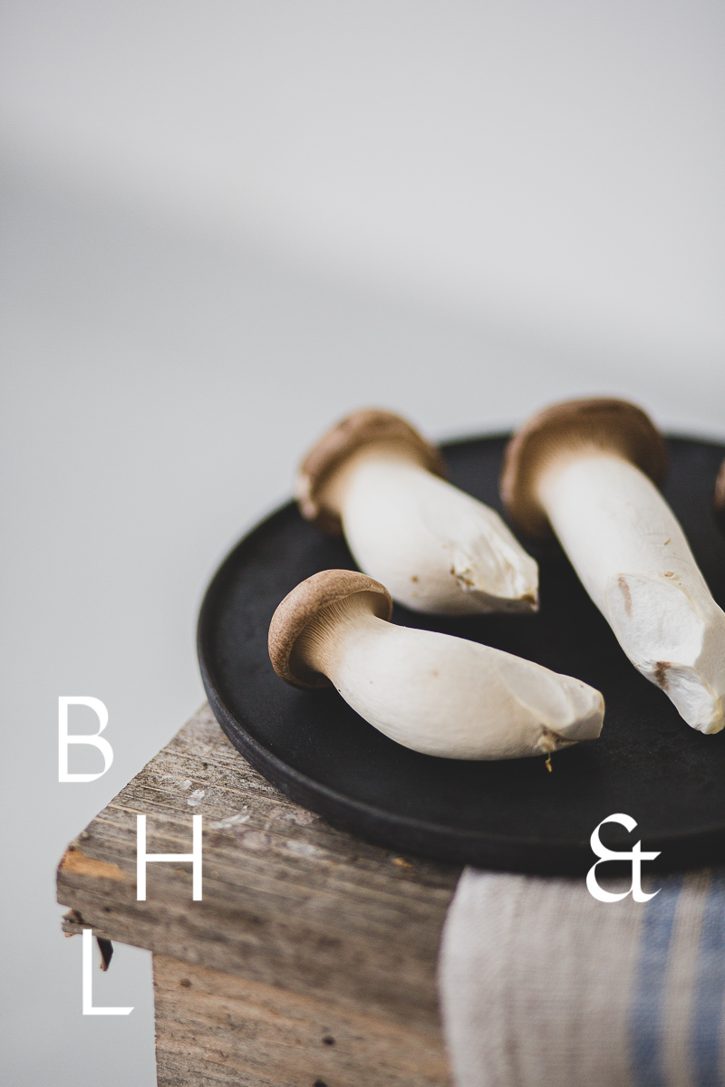 Food photography of french horn mushroom on a black plate with natural tones towels on a bench as a close up in perspective