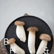 Food photography of french horn mushroom on a black plate with natural tones towels on a bench as a table top shot