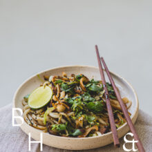 Food photography of Thai noodles with lime and Thai basil on a white ceramic plate with chopsticks on a linen tablecloth shoot in perspectivet
