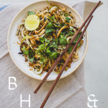 Food photography of Thai noodles with lime and Thai basil on a white ceramic plate with chopsticks on a linen tablecloth as a table top shoot