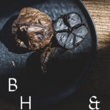 Food photography of black garlic on a black plate cut open