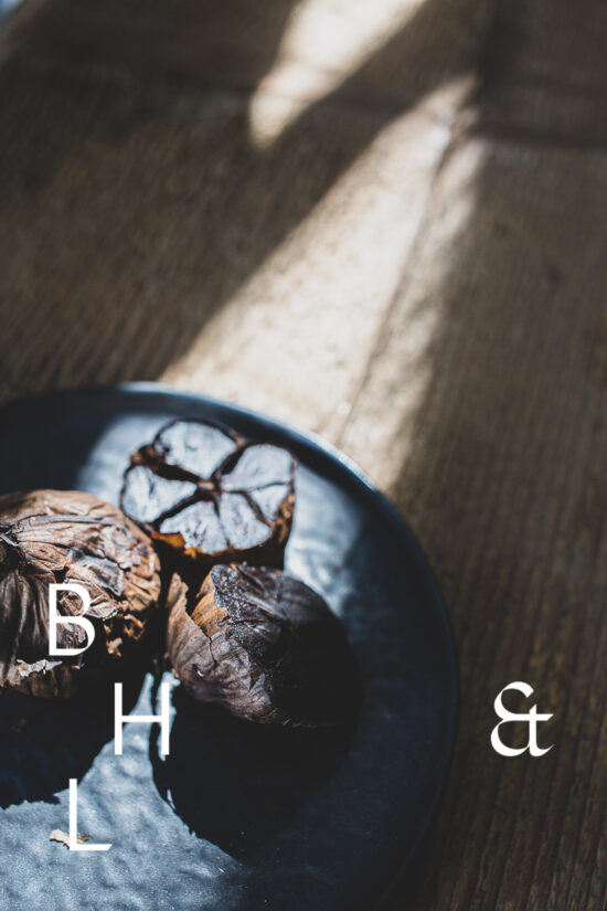 Food photography of black garlic on a black plate cut open