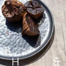 Food photography of black garlic on a black plate cut open