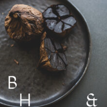 Food photography of black garlic on a black plate cut open