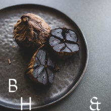 Food photography of black garlic on a black plate cut open
