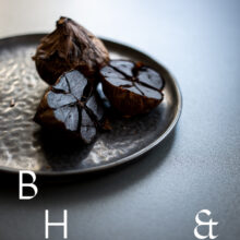 Food photography of black garlic on a black plate cut open