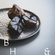 Food photography of black garlic on a black plate cut open