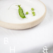 Food photography of a pea pod on a white plate on a white table clove in perspective