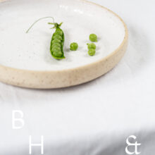 Food photography of a pea pod on a white plate on a white table clove in perspective
