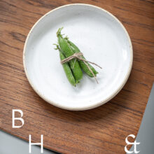 Food photography of a pea pod on a white plate on a wooden chair from above