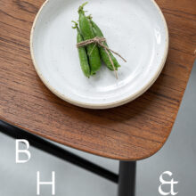 Food photography of a pea pod on a white plate on a wooden chair from above