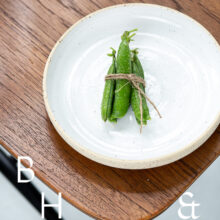Food photography of a pea pod on a white plate on a wooden chair from above