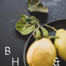 Food photography of lemons and lemon leaves on a black plate set on a black table