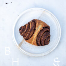 Food photography of a cinnamon rolls on a white plate on light marble and some crumbs
