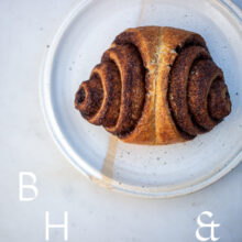 Food photography of a cinnamon roll on a white plate and light marble