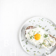 Clean food photography with a sandwich and a sunny side up on a white plate