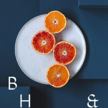 Food photography of Oranges cut half open on a white plate on blue ground