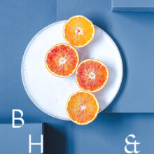 Food photography of Oranges cut half open on a white plate on blue ground
