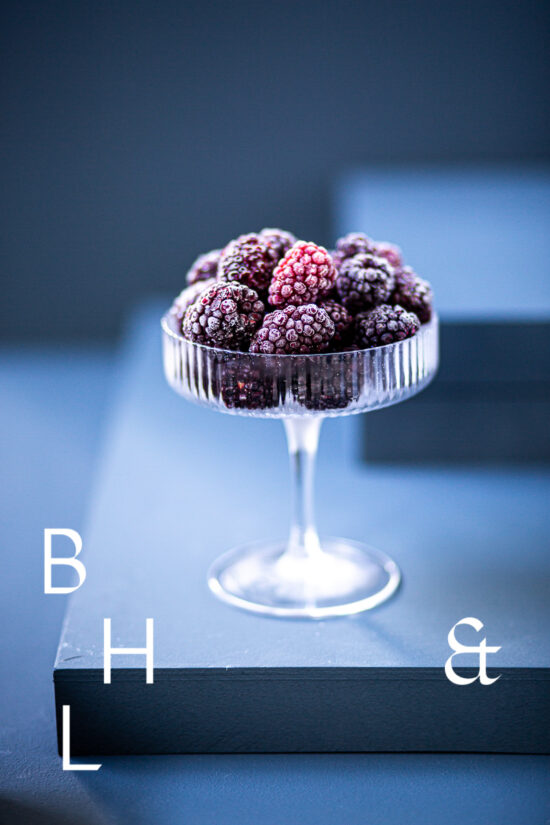 Food photography of frozen blackberries in a frozen glas on a blue background