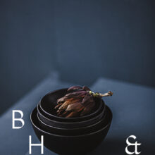Food photography of artichoke in black ceramic bowels on a grey ground
