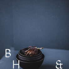 Food photography of artichoke in black ceramic bowels on a grey ground