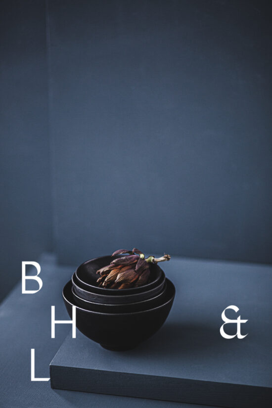 Food photography of artichoke in black ceramic bowels on a grey ground