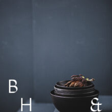 Food photography of artichoke in black ceramic bowels on a grey ground
