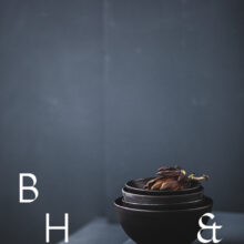Food photography of artichoke in black ceramic bowels on a grey ground