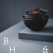 Food photography of artichoke in black ceramic bowels on a grey ground