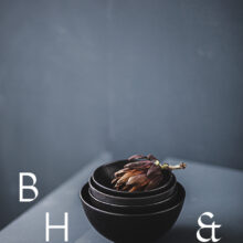 Food photography of artichoke in black ceramic bowels on a grey ground