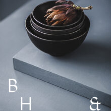 Food photography of artichoke in black ceramic bowels on a grey ground