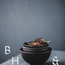 Food photography of artichoke in black bowels on a grey ground